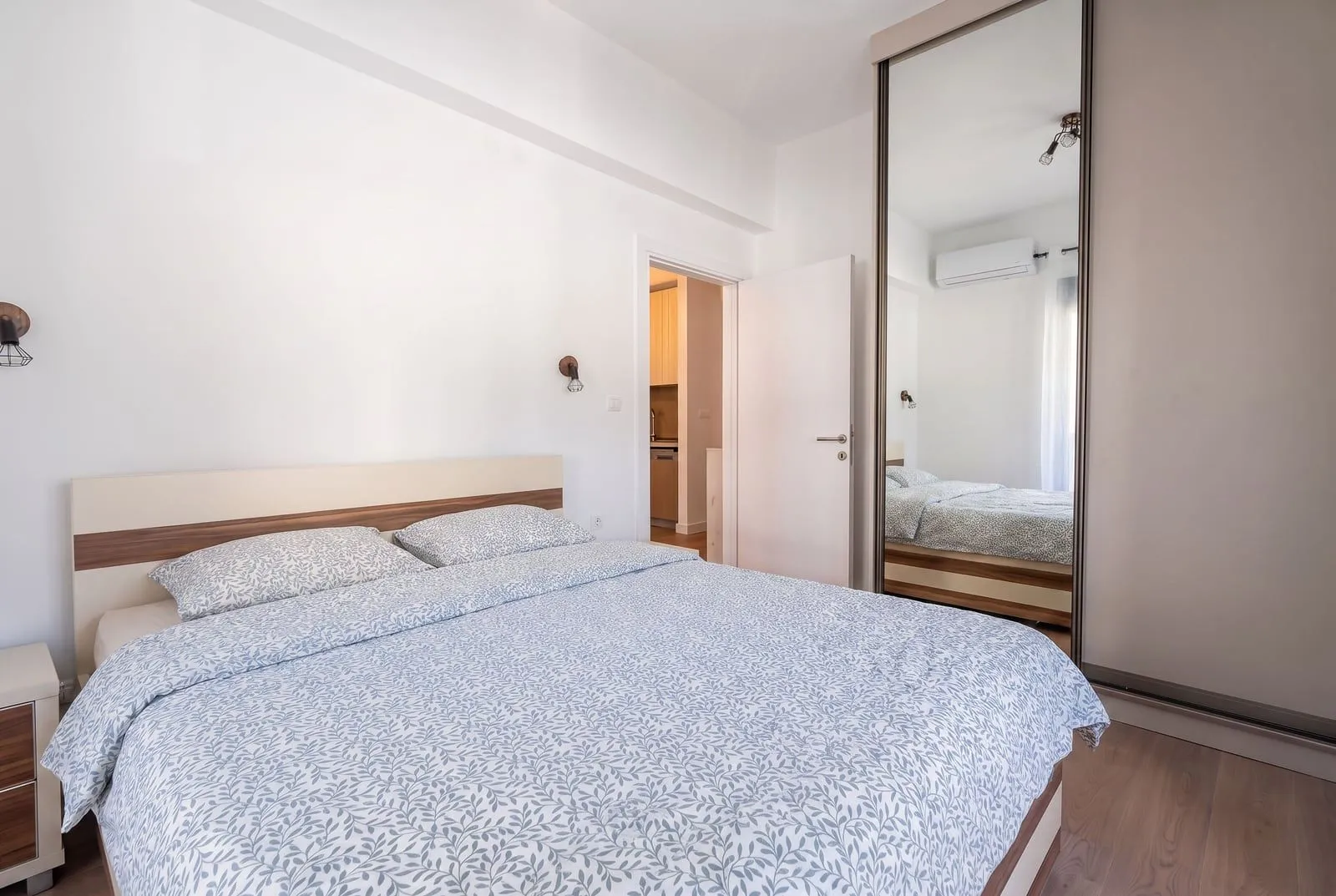 Bright bedroom with a double bed and a fitted wardrobe with a mirror.