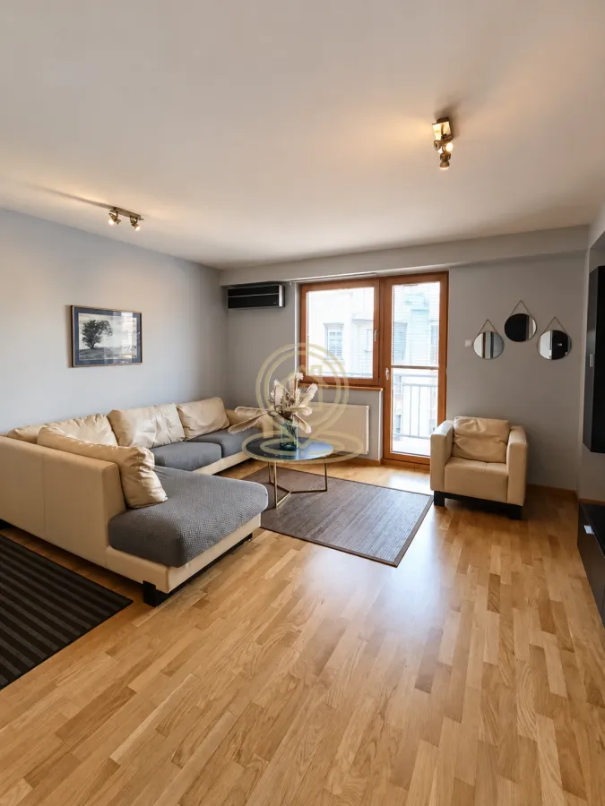 Living room with a sectional sofa, armchair, and parquet flooring.
