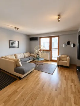 Living room with a sectional sofa, armchair, and parquet flooring. - image 2