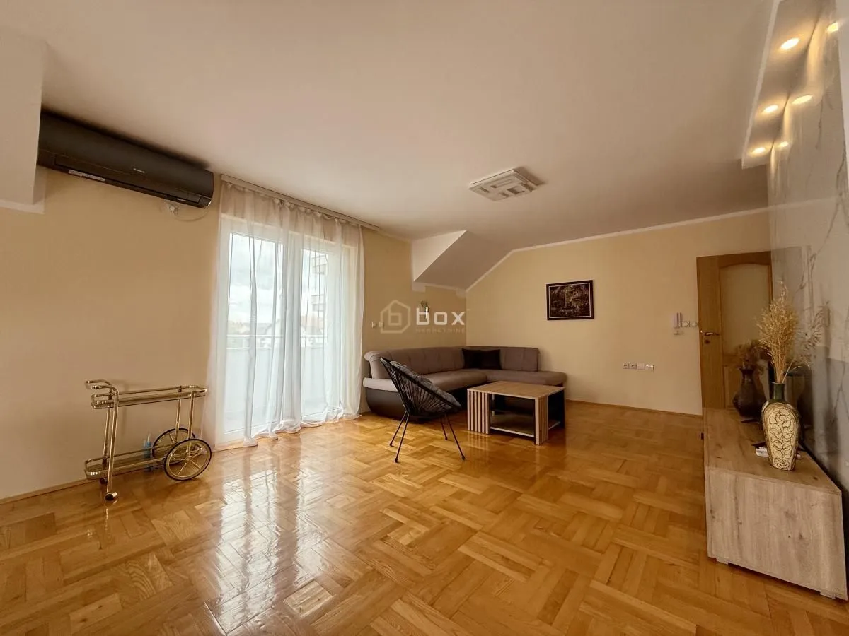 Spacious living room with sofa, parquet flooring, and access to the terrace.
