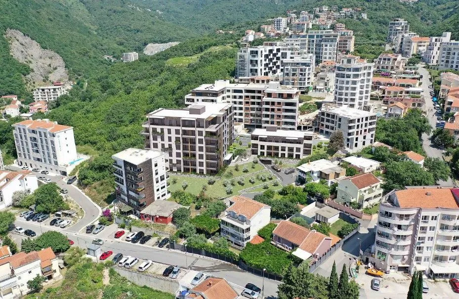 Pogled iz vazduha na stambeni kompleks i okolno naselje sa zelenilom.