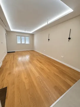 Empty room with wooden parquet flooring, white walls, and a drop ceiling with lighting. - image 3