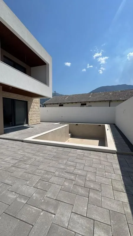 Pogled na dvorište sa bazenom i popločanim platoom ispred kuće.