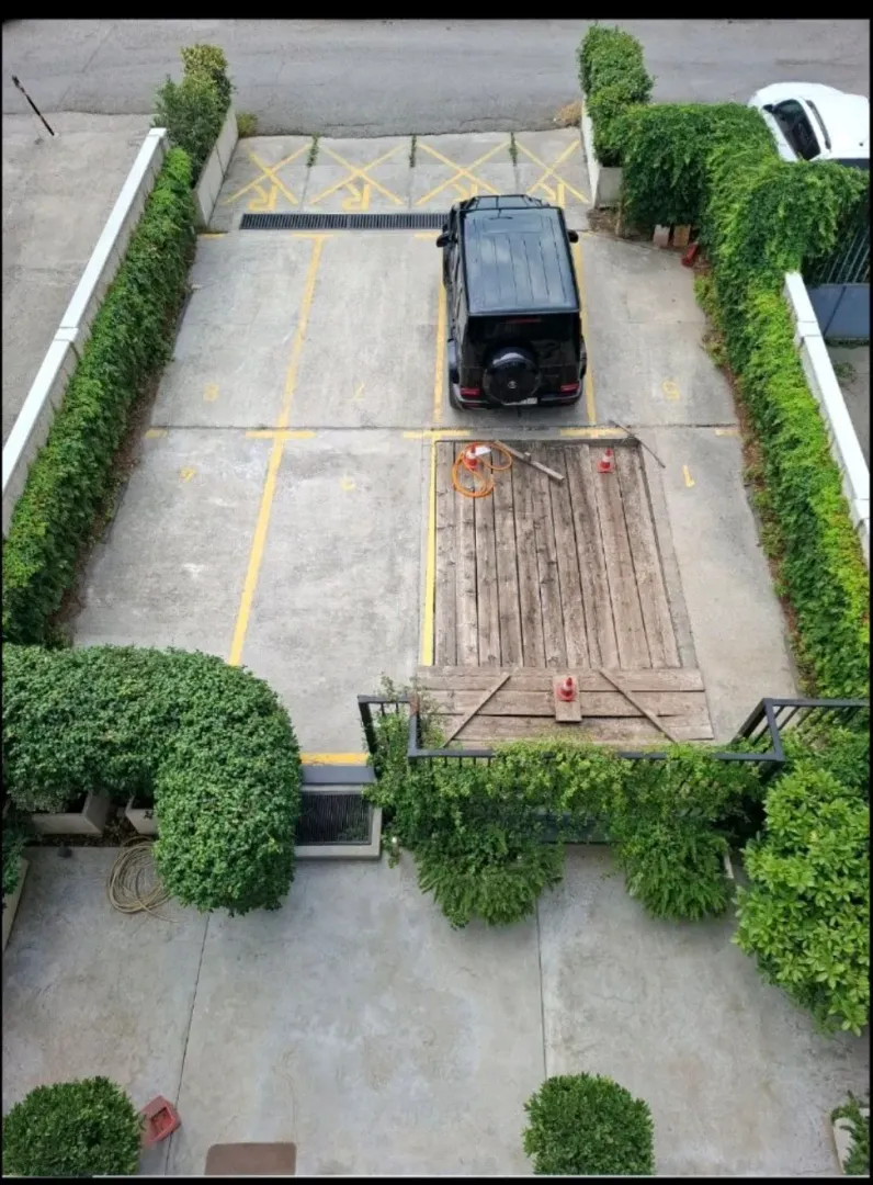 Top-down view of a parking area with marked spaces and a vehicle.