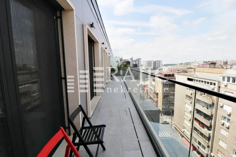 Long balcony with a glass railing and a city view.