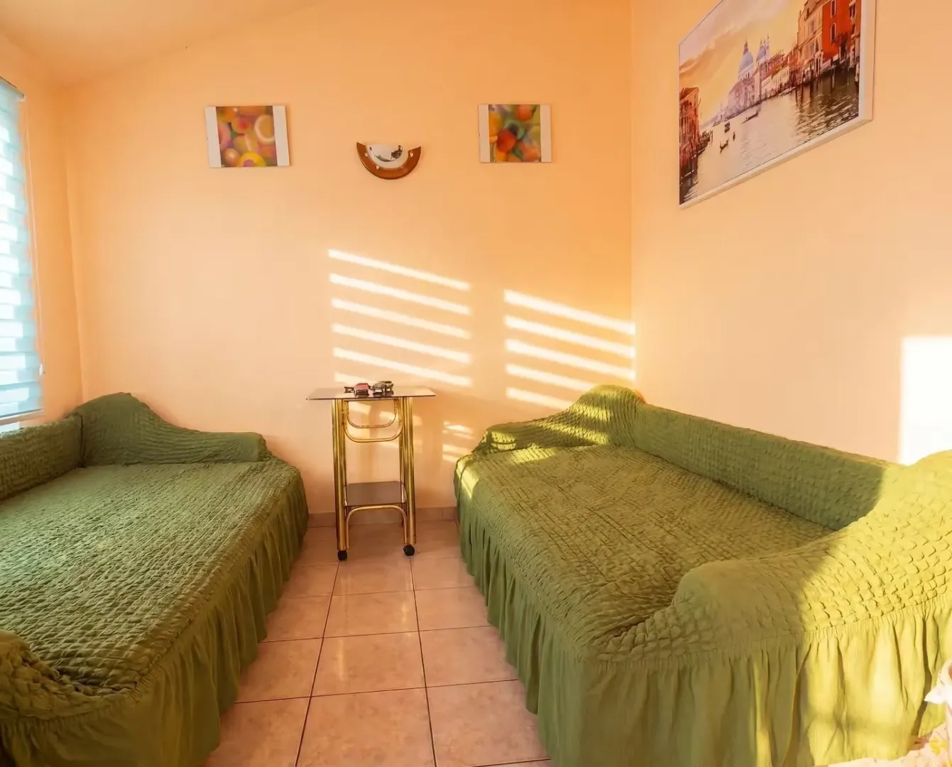 Living room with two green sofas and wall paintings.
