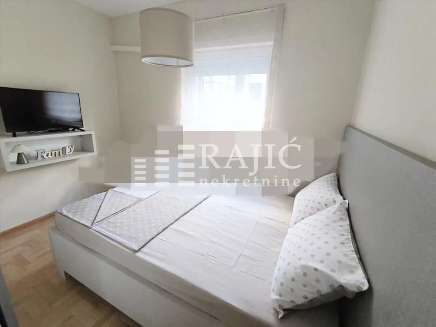Furnished bedroom with a double bed and television.