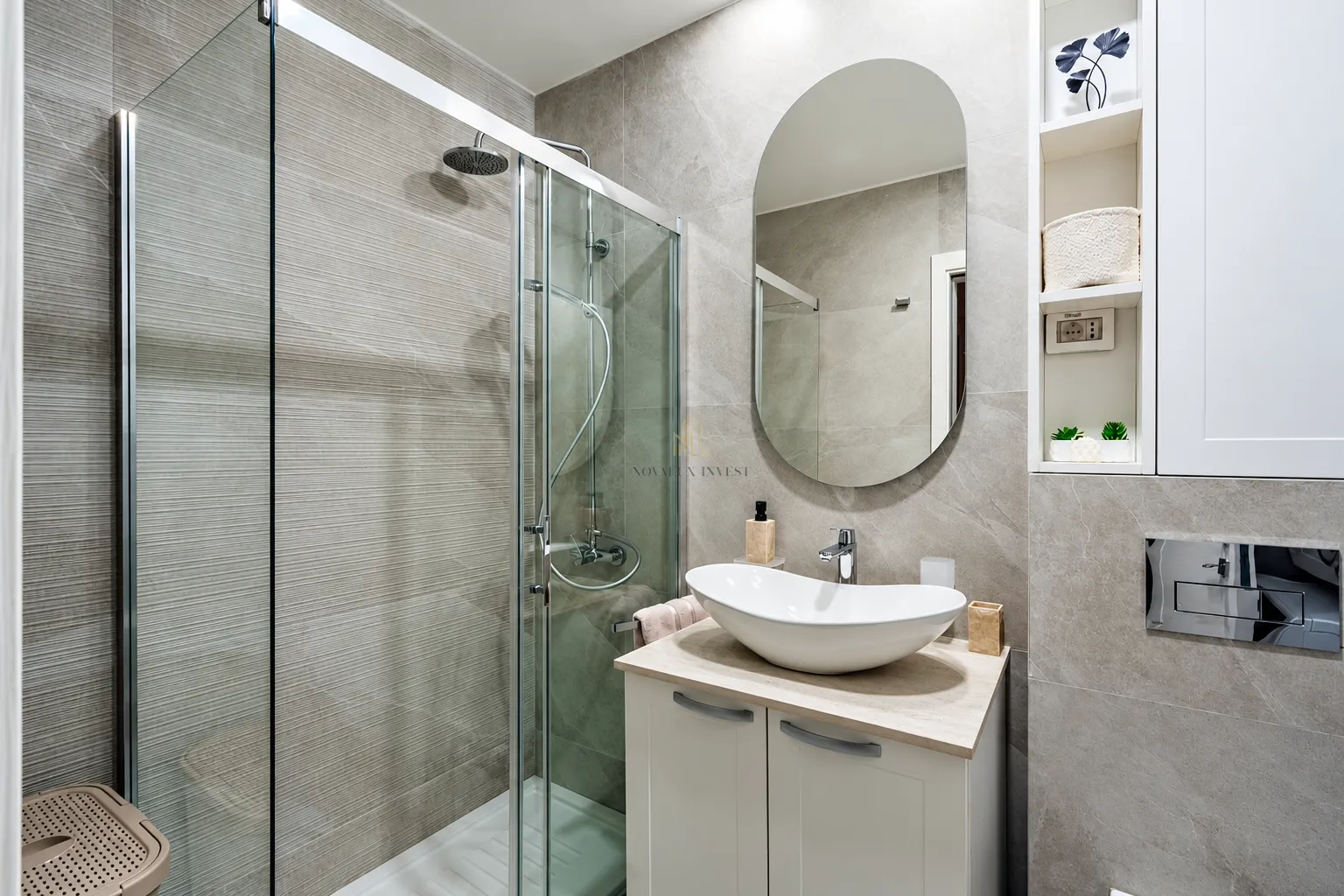 Modern bathroom with a shower cabin, washbasin, and a large mirror.