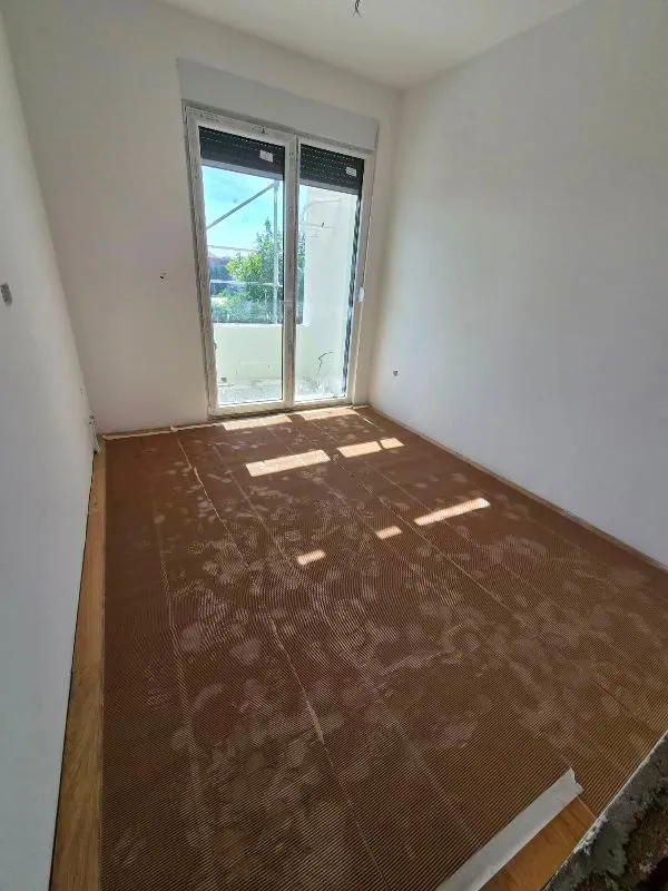 Neopremljena prostorija sa balkonskim vratima i podnom oblogom u toku ugradnje.