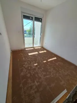 Neopremljena prostorija sa balkonskim vratima i podnom oblogom u toku ugradnje. - image 3