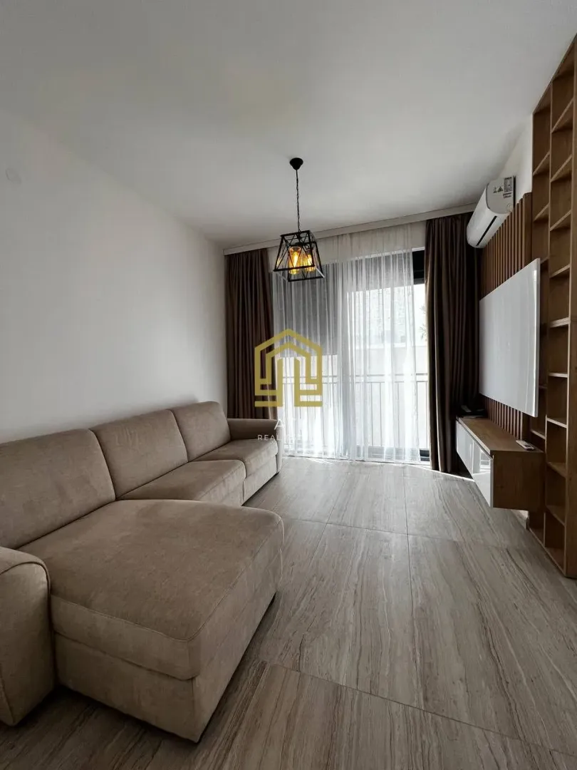 Moderan dnevni boravak sa garniturom i drvenim oblogama na zidu.