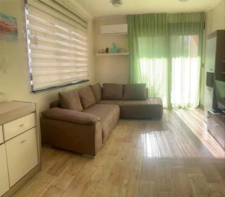 Living room with a corner sofa, TV unit and a large window.