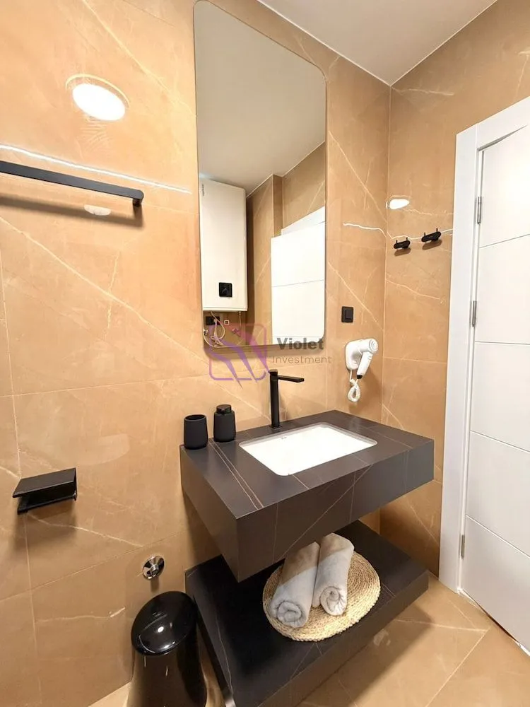 Modern bathroom with a washbasin, mirror and beige tiles.