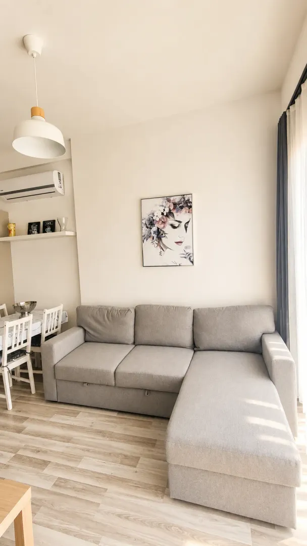 Living room with a sectional sofa, dining area, and air conditioning.