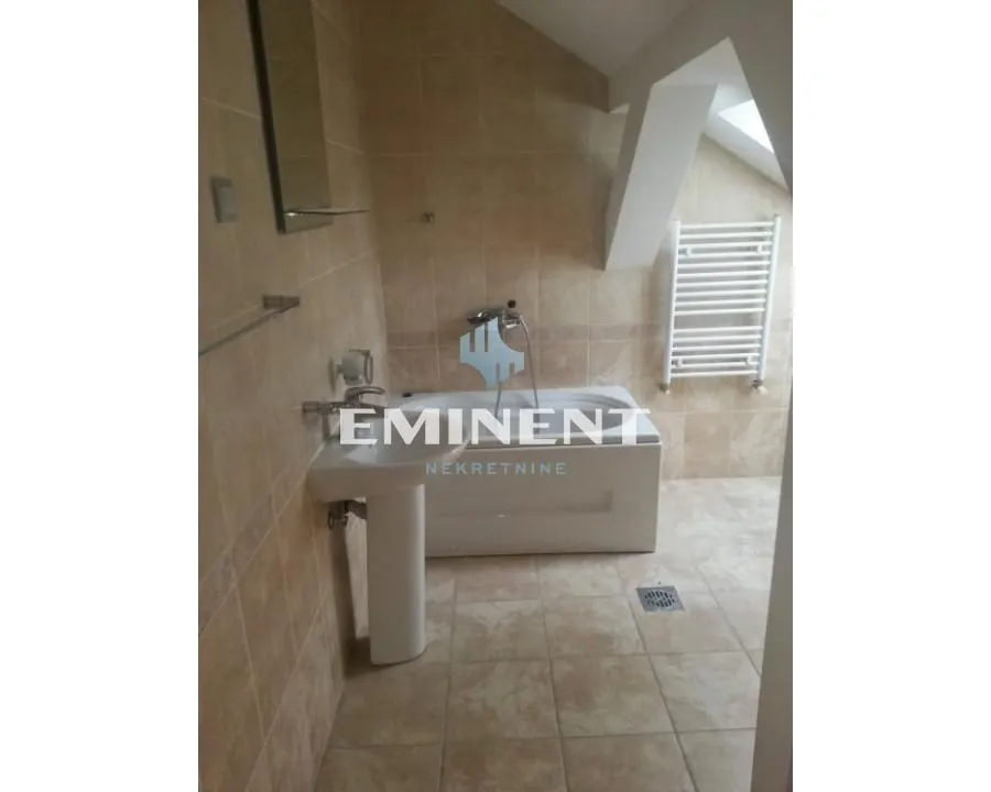 Tiled bathroom with a bathtub and a washbasin.