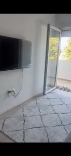Dnevna soba sa televizorom na zidu i izlazom na terasu.