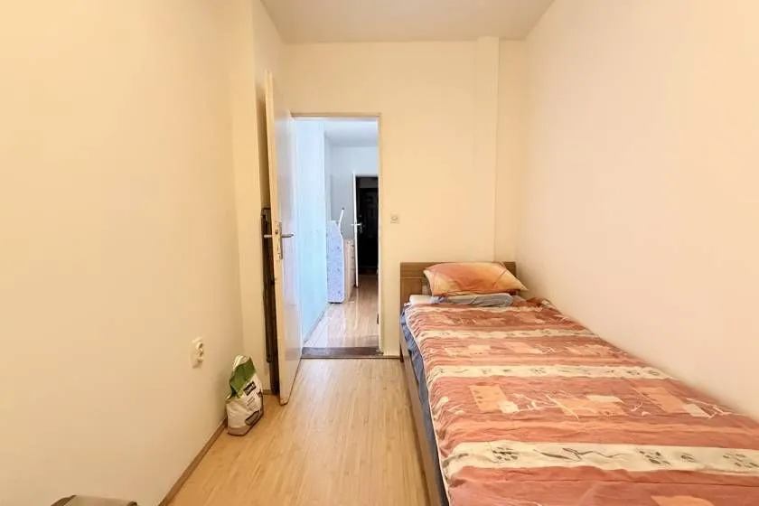 Manja spavaća soba sa krevetom i pogledom prema hodniku.