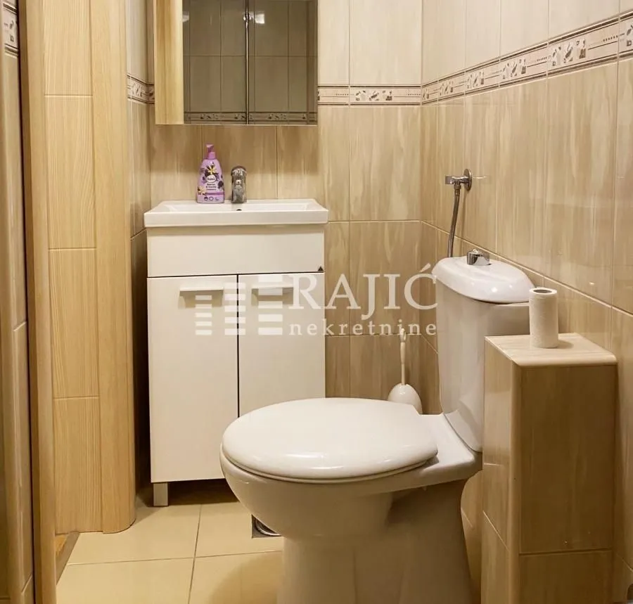 Smaller bathroom with a sink, toilet, and wall cabinet.