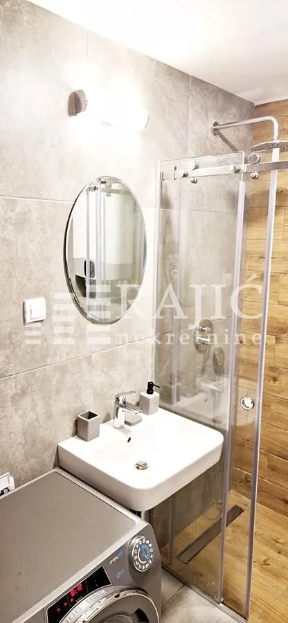 Modern bathroom with a sink, mirror, and walk-in shower.