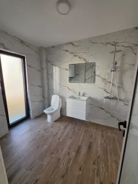 Modern bathroom with marble-patterned tiles, sink, shower, and toilet. - image 12