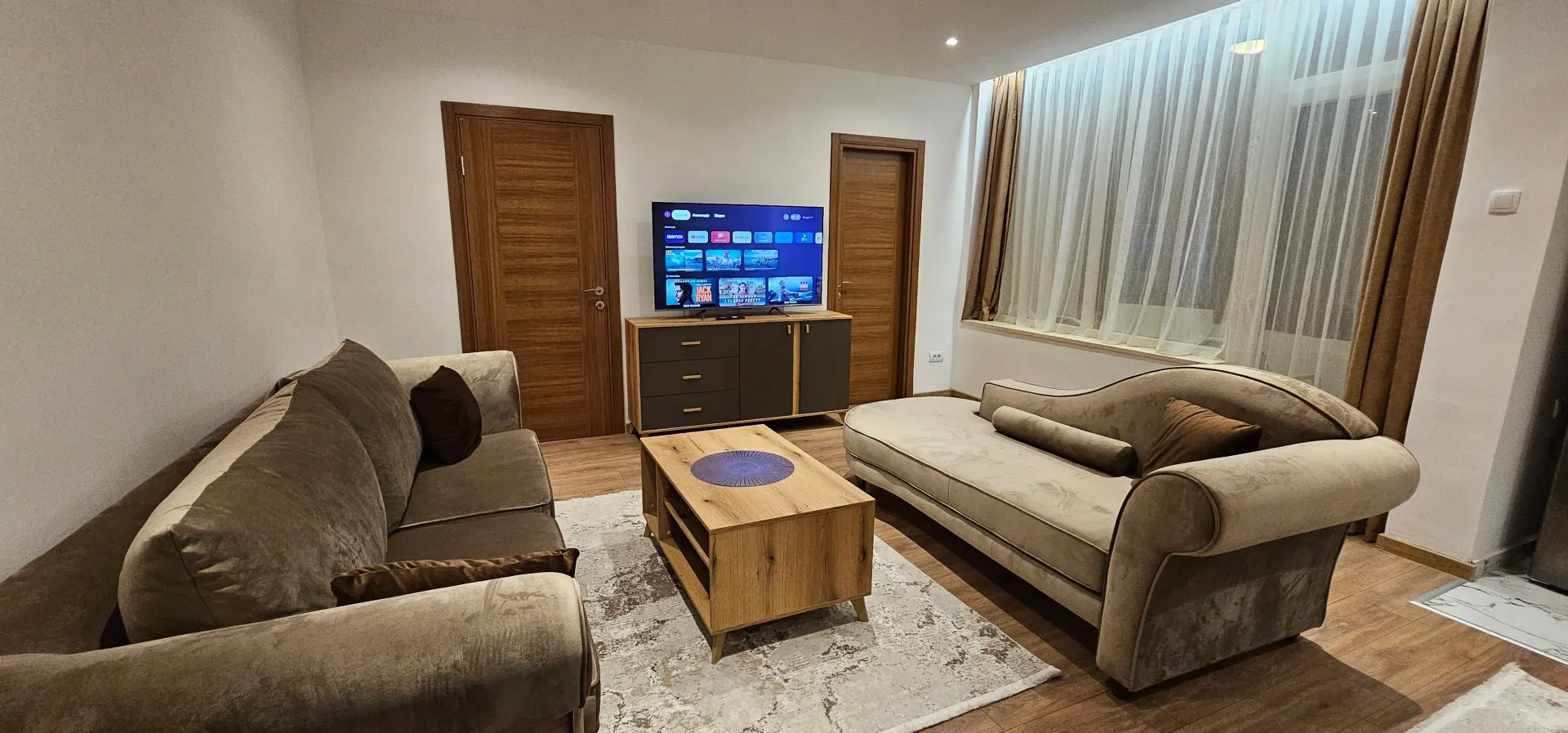 Namještena dnevna soba sa garniturom, stočićem i televizorom.