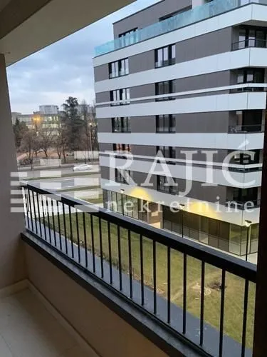 Pogled sa balkona na susednu stambenu zgradu i ulicu.