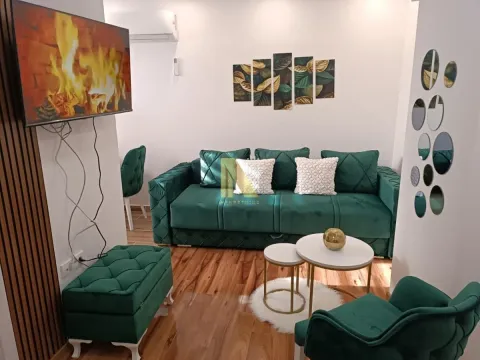Dnevna soba sa zelenom garniturom, stočićem i televizorom na zidu. - image 2
