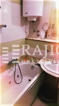 Smaller bathroom with a bathtub, washbasin, and water heater. - image 10