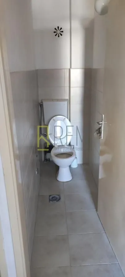 Manje kupatilo sa toaletom u svijetlim pločicama.