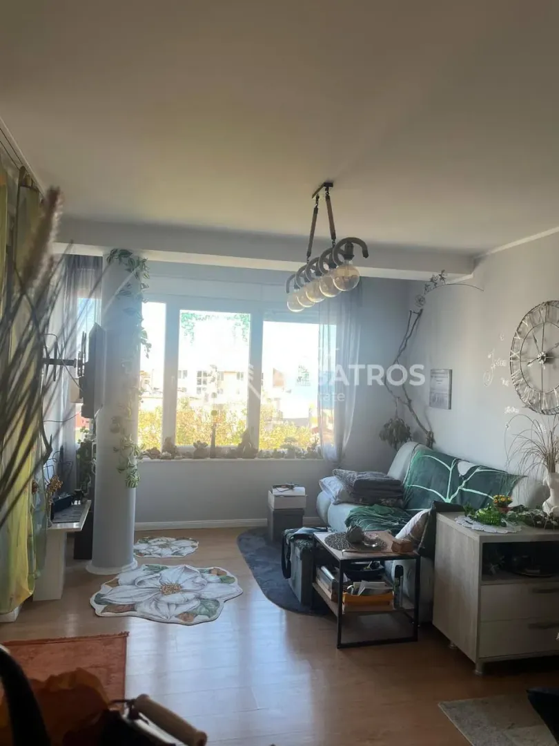 Namješten dnevni boravak sa garniturom i velikim prozorom.