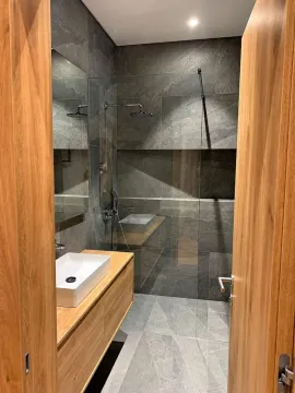 Modern bathroom with a walk-in shower, washbasin, and grey tiles. - image 13