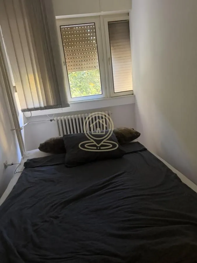 Manja spavaća soba sa krevetom i prozorom.