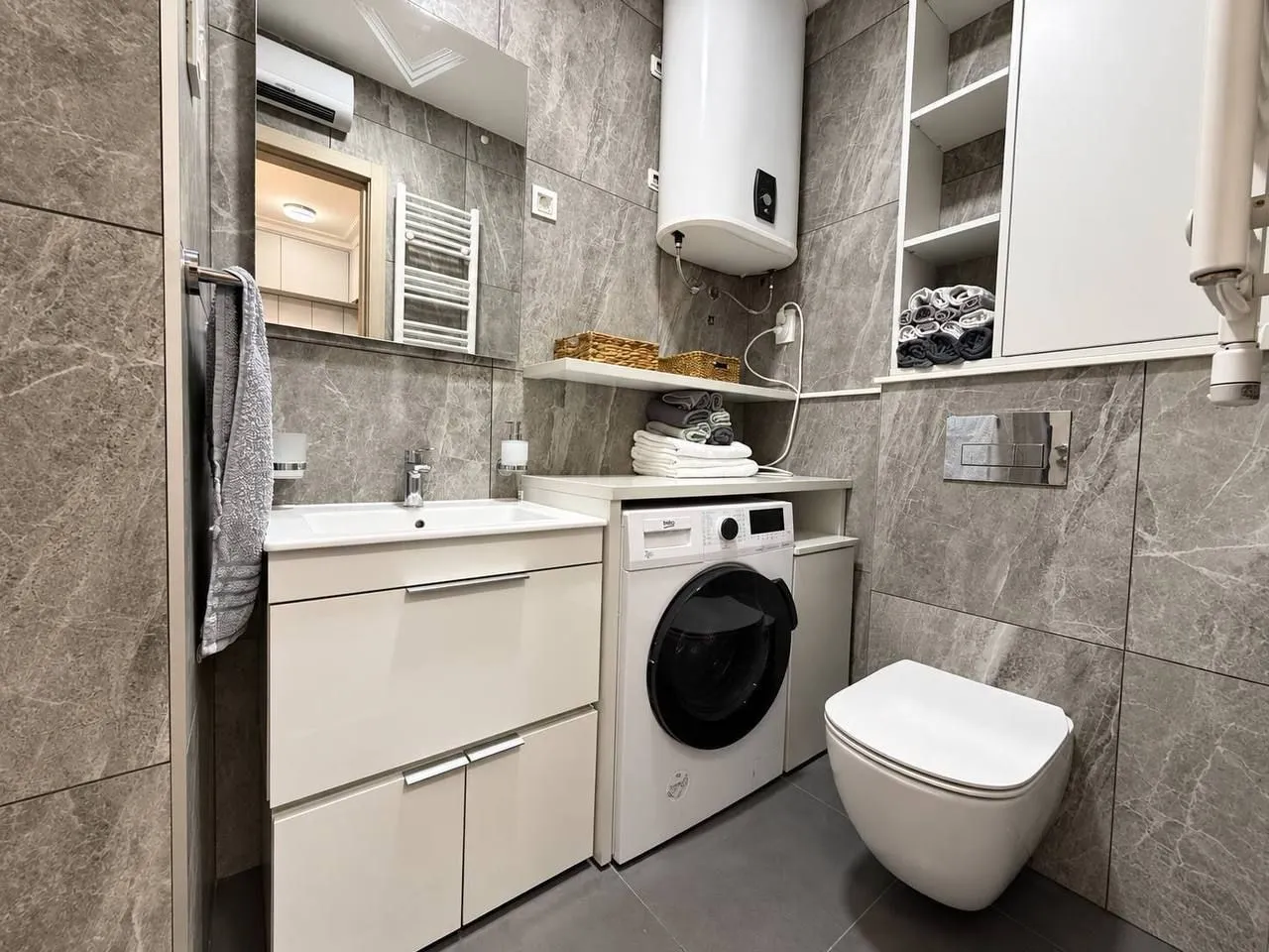 Moderno opremljeno kupatilo sa umivaonikom, veš mašinom i WC šoljom.
