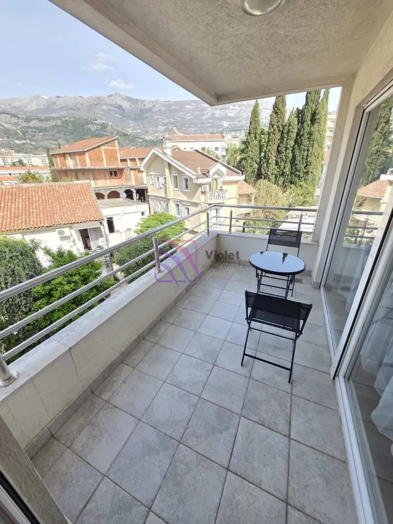 Covered balcony with seating set and a view of the surroundings and mountains.