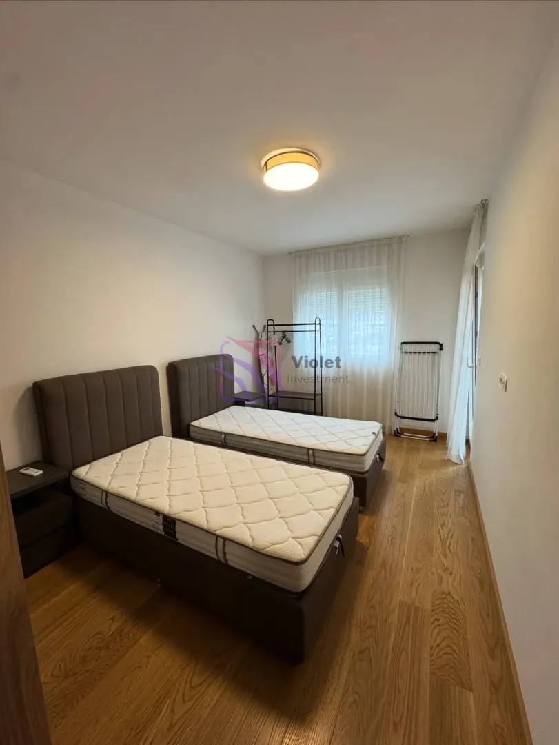 Spavaća soba sa dva singl kreveta i drvenim podom.