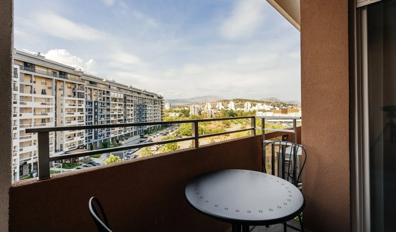 Furnished balcony with a table and chairs and a city view.