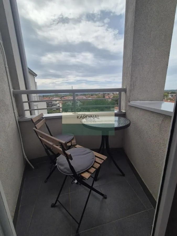 Manji natkriveni balkon sa garniturom za sedenje i pogledom na okolinu.