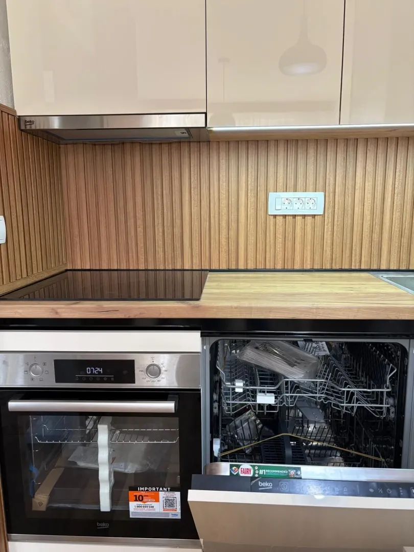 Modern kitchen featuring built-in appliances and a wooden backsplash.