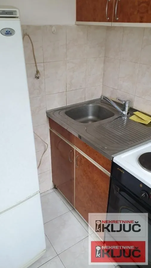 Manja kuhinja sa sudoperom, elementima i šporetom.