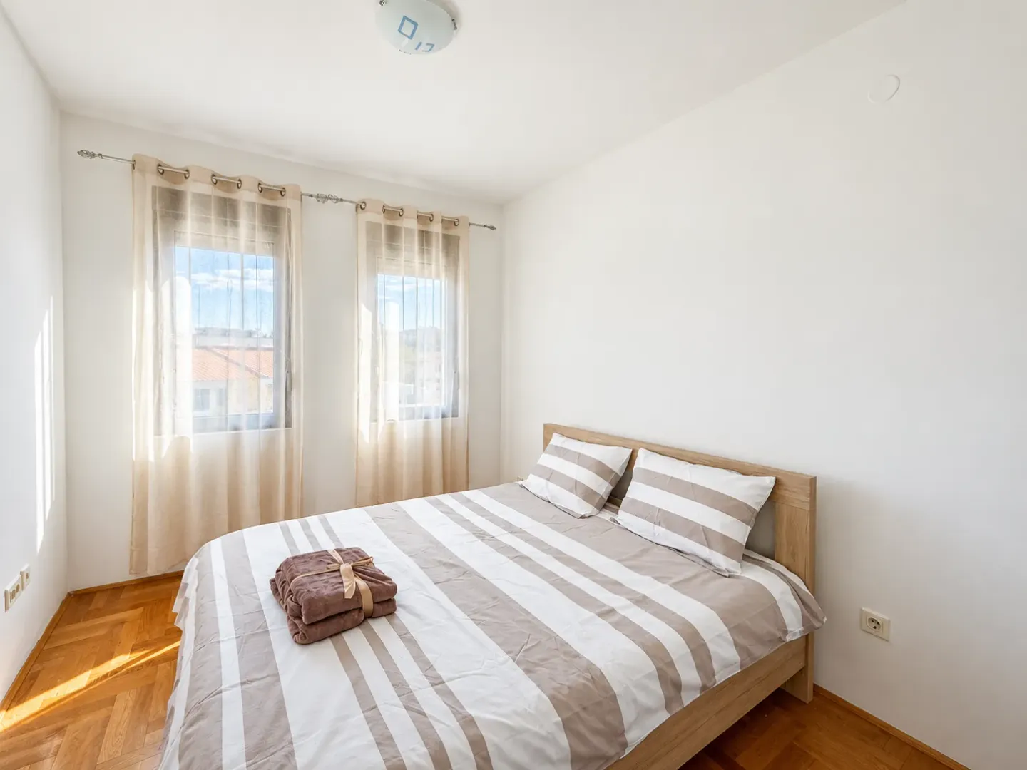 Bright bedroom with a double bed and two windows.