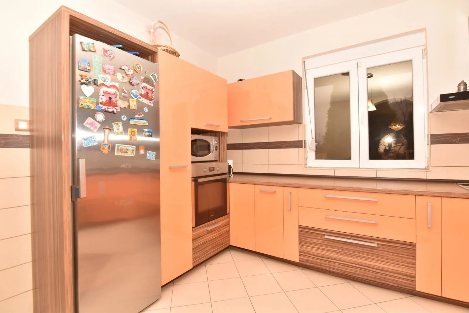 Kitchen with orange cabinets and a refrigerator covered with magnets.