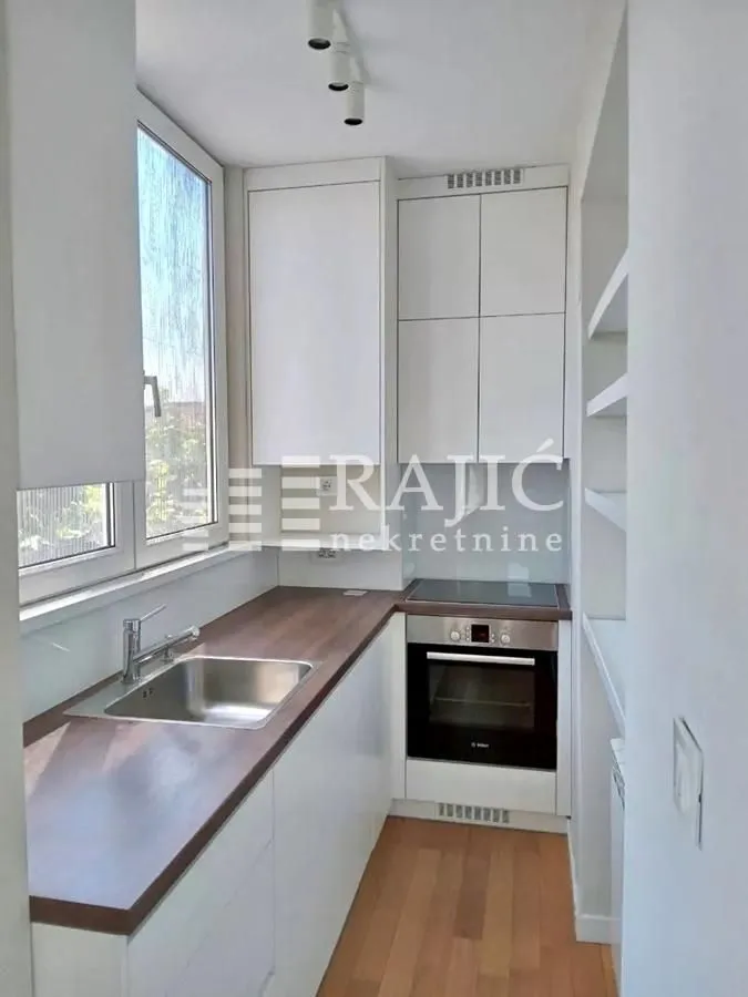 Compact white kitchen with a wooden countertop and built-in oven.