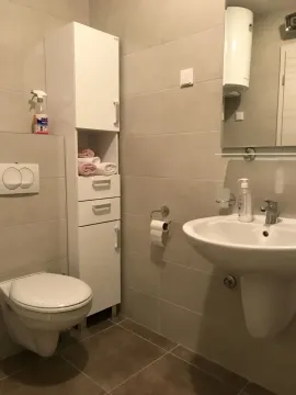Bright bathroom with a sink, toilet, and a tall white cabinet. - image 3