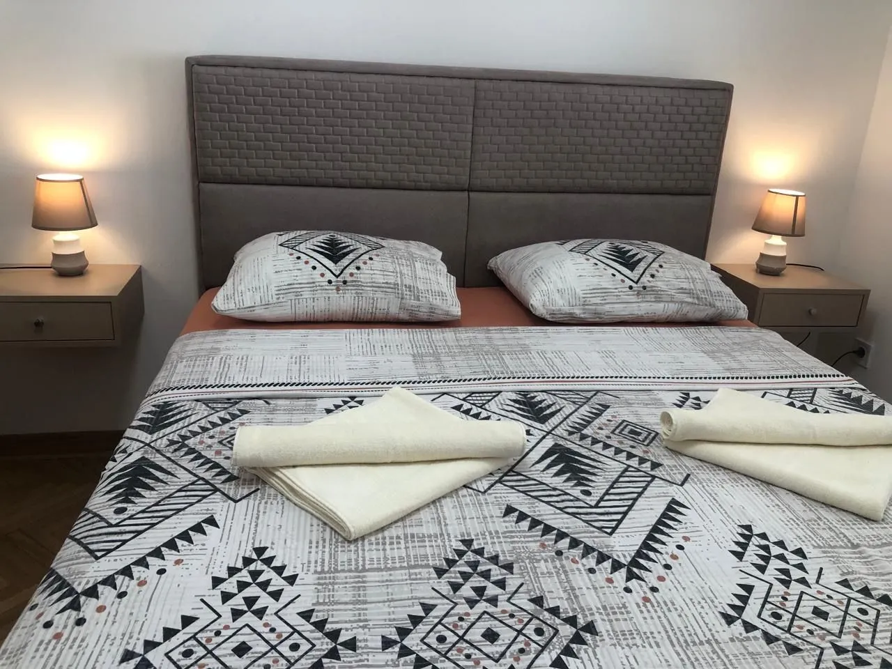 Furnished bedroom with a double bed and bedside tables with lamps.
