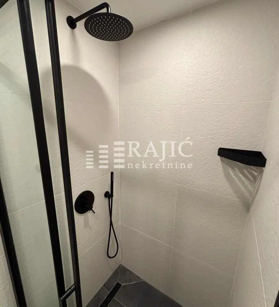 Modernly equipped bathroom with a shower cabin and black fixtures.