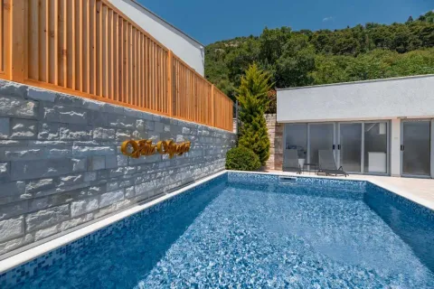 Exterior area with a swimming pool, stone wall, and wooden fence. - image 12