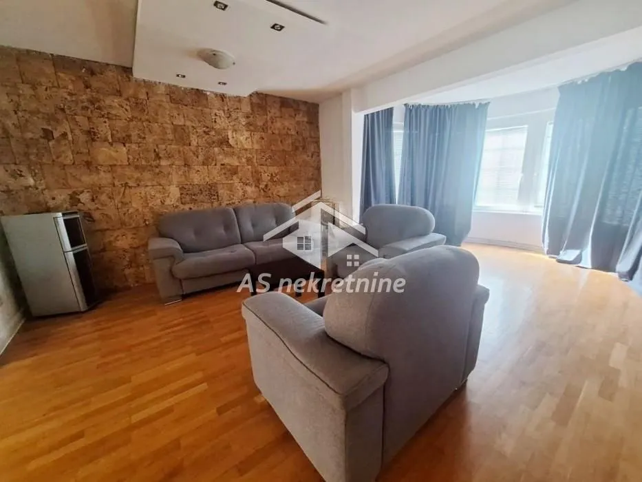 Living room with seating furniture and a stone wall.