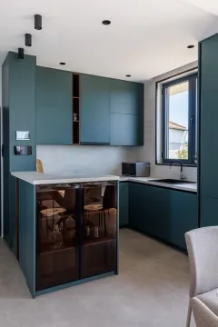 Modern kitchen with dark green cabinetry and a dining area. - image 9