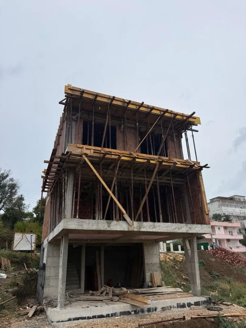 View of a house under construction with concrete structure and scaffolding.