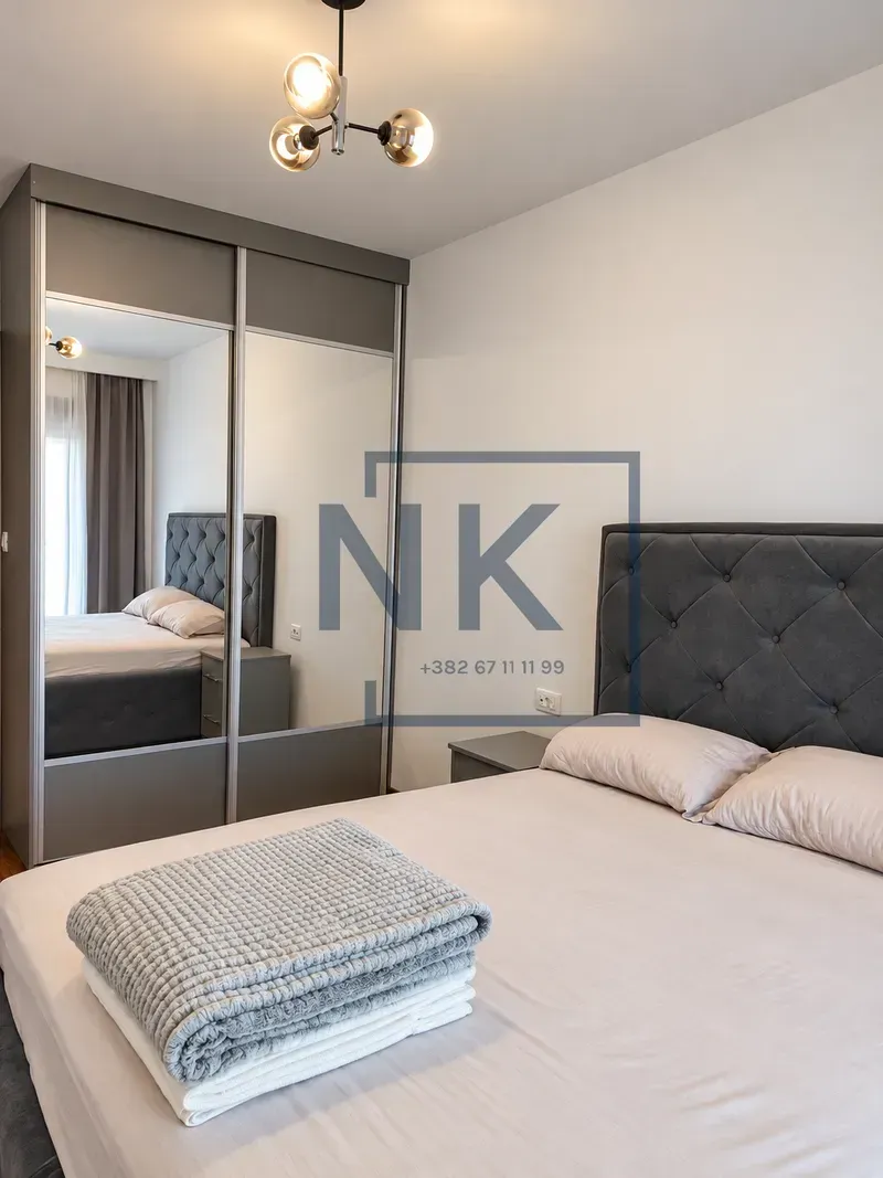 Furnished bedroom with a double bed, mirrored wardrobe, and a chandelier.